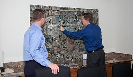 Two men in business clothes looking at map with one of them pointing at the map